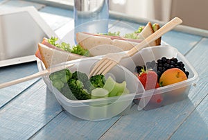 Lunch box with sandwich, vegetables, fruits and bottle of water