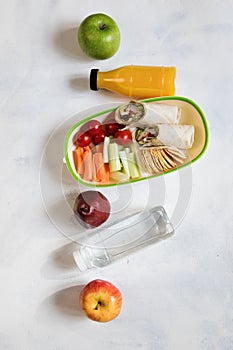 Healthy lunch box with sandwich and fresh vegetables, fruits, bottle of water and juice. from top view