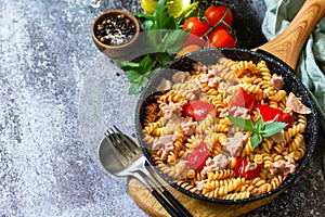 Healthy lunch. Fusilli pasta with canned tuna, grilled red peppers and tomatoes in frying pan on a stone countertop.