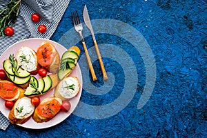 Healthy lunch with mini sandwiches cheese, fish and avocado on blue background top view space for text