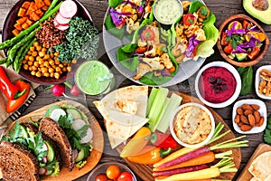 Healthy lunch table scene with nutritious Buddha bowl, lettuce wraps, vegetables, sandwiches and salad, above view over wood