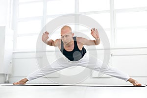 healthy male stretching, doing hard yoga exercises