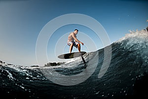 healthy man riding on the wave with hydrofoil foilboard on background of blue sky