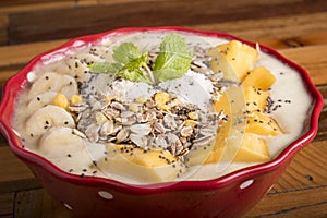 healthy mango bannana smoothie bowl with wooden background