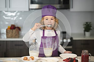 Healthy meal and dinner preparation. Chef child cook baking on the kitchen, lick spoon .