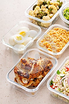 Healthy meal prep with cooked chicken breast, boiled eggs, roasted vegetables, cooked lentils, couscous salad and nuts