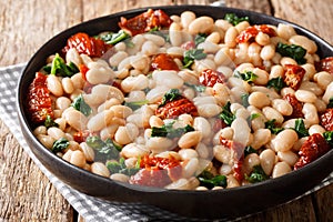 Healthy meal of white beans with spinach, garlic and sun-dried tomatoes closeup on a plate. horizontal