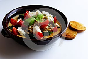 Healthy Meals: barley soup in a bowl with chick peas, spinach, feta cheese, cherry tomatoes, basil and toasted bread.