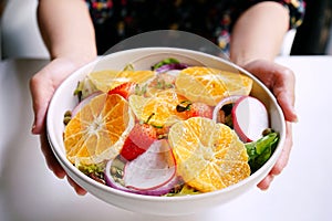 Healthy meals, A female uses hands to holding and handing a dish of mixed salad with preserved salmon,