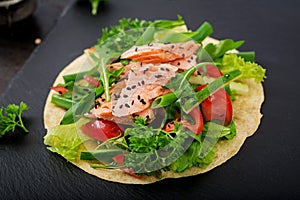 Healthy mexican corn tacos with baked salmon, lettuce, tomato, cucumber