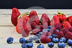 Healthy mixed fruit and ingredients with strawberry, raspberry, blueberry. Berries on rustic white wooden background