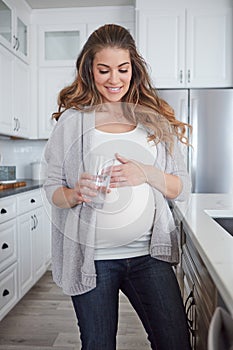 A healthy mom A healthy baby. 4k video footage of a pregnant woman drinking a glass of water at home.