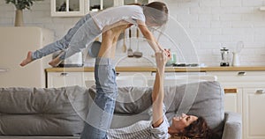 Healthy mom and little daughter practice acro yoga at home