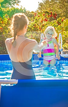 Healthy mother and child in swimsuit in swimming pool playing