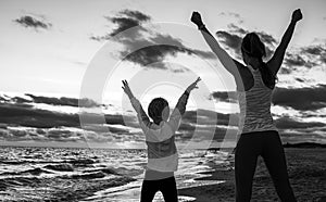 Healthy mother and daughter on seacoast on sunset rejoicing