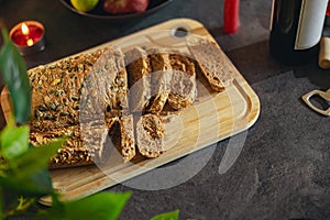 Healthy multi grain cut bread with seeds on a wooden board is standing on festive table