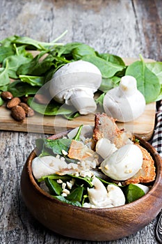 Healthy mushroom salad with spinach and bacon on wooden table
