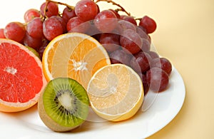 Healthy natural food. Vitamin plate. Sliced citrus fruits, orange, lemon, kiwi, grapes on a white plate