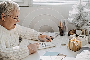 Healthy New Years resolutions for older adults. Senior mature old woman in white sweater writing handwritten text 2022