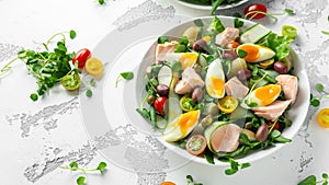 Healthy Nicoise salad with salmon, colourful sweet cherry tomatoes, olives, green beans, cucumber ribbons, soft boiled