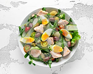 Healthy Nicoise salad with salmon, colourful sweet cherry tomatoes, olives, green beans, cucumber ribbons, soft boiled