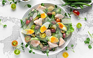 Healthy Nicoise salad with salmon, colourful sweet cherry tomatoes, olives, green beans, cucumber ribbons, soft boiled