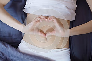 Healthy nutrition and belly health concept. Close up of woman flat stomach. Girl in bed with hungry feeling. Top view