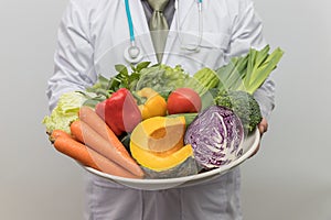 Healthy and nutrition concept. Doctor holding bowl of fresh fruits and vegetables