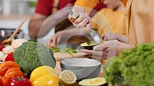 Healthy nutrition for family. Close up shot of woman peeling avocado, her husband and little daughter cutting vegetables