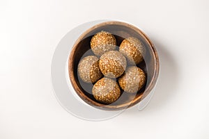 Healthy and nutritious Til Laddu- sesame seed dessert served in a wooden bowl. photo