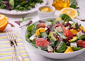 Healthy orange, avocado, grapefruit and pomegranate salad with honey and mustard dressing.