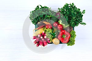 Healthy organic food background. Green wooden box full of fresh farm raw vegetables from local farmer market on white wooden