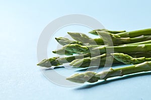 Healthy organic green asparagus stalks ready to cook on blue background