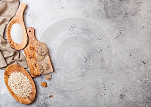 Healthy organic oat cookies with chocolate on wooden board on stone kitchen table background. Sugar and raw oats in olive wooden b