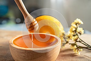 Healthy organic scoop Thick honey dipping with wooden honey spoon from a wooden bowl, honey dripping, pouring honey into the bowl