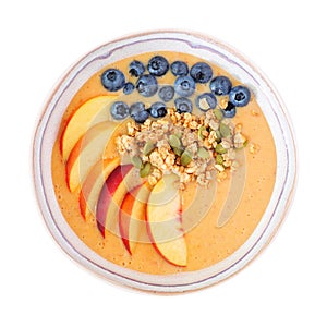 Healthy peach smoothie bowl with blueberries and granola isolated on white