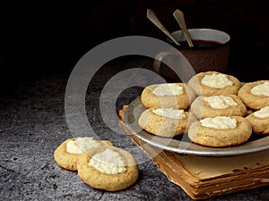 Healthy Peanut Butter Cheesecake Thumbprint Cookies. Delicious homemade shortbread and cup of tea on dark background. Copy space.