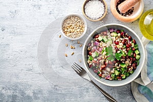 Healthy pearl barley salad with beans, cucumbers, red onion, sunflower seeds, pomegranate and parsley in bowl