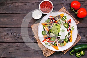 Healthy, plant based bell pepper nachos. Overhead view table scene on a dark wood background.