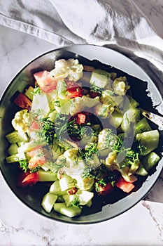 Healthy plant salad with cauliflower, tomatoes, cucumber, almond and dill