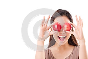 Healthy and playful woman covering her eyes with two red apples