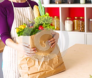 Healthy positive happy woman holding a paper shopping bag full of fruit and vegetables