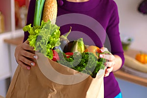 Healthy positive happy woman holding a paper shopping bag full of fruit and vegetables