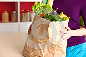 Healthy positive happy woman holding a paper shopping bag full of fruit and vegetables