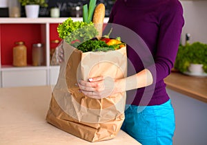 Healthy positive happy woman holding a paper shopping bag full of fruit and vegetables