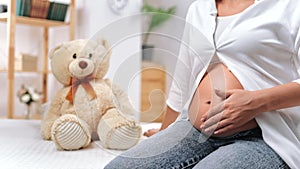 Healthy pregnancy and happy motherhood, close-up view of big belly of pregnant woman and teddy bear