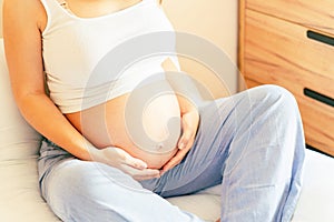 Healthy pregnancy meditation. Beautiful pregnant woman meditating while sitting in lotus position. Health yoga home