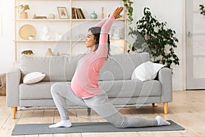 Healthy pregnant black woman exercising at home, doing yoga