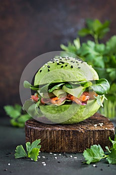 healthy raw avocado burger with salted salmon and fresh vegetables. selective focus