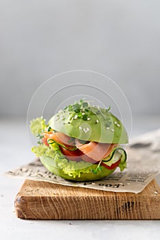 Healthy raw avocado burger with salted salmon, fresh vegetables and microgreen. Raw food diet recipe, healthy nutrition. Side view